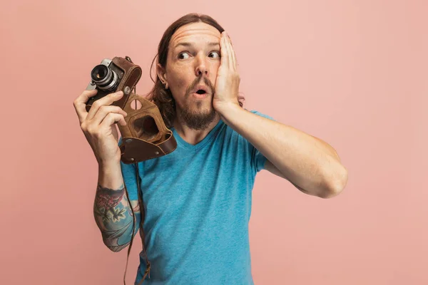 Portret van jongeman, fotograaf, cameraman met retro camera geïsoleerd op roze studio achtergrond. Concept van beroep, baan, grappige meme emoties — Stockfoto