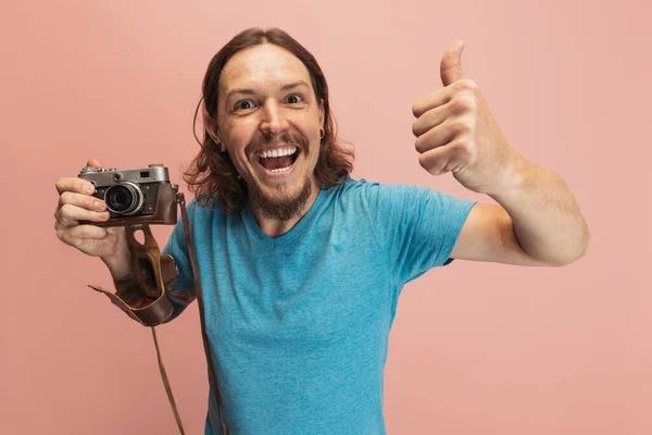 Retrato de joven, fotógrafo, camarógrafo con cámara retro aislada sobre fondo de estudio rosa. Concepto de ocupación, trabajo, emociones divertidas meme — Foto de Stock