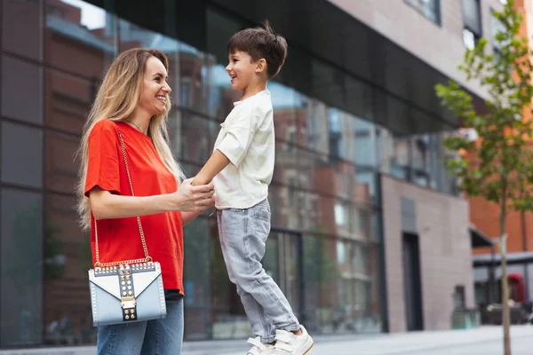 Duas pessoas, mãe e pequeno filho bonito passeando na rua, praça de comércio no verão, ao ar livre. Tempo de família, união, parentalidade e conceito de infância feliz. — Fotografia de Stock