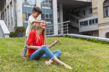 Mutlu bir anne ve küçük sevimli bir oğul yazın açık havada, halka açık bir parkta geziniyor. Aile zamanı, birliktelik, ebeveynlik ve mutlu çocukluk kavramı..
