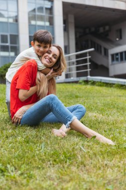 Mutlu bir anne ve küçük sevimli bir oğul yazın açık havada, halka açık bir parkta geziniyor. Aile zamanı, birliktelik, ebeveynlik ve mutlu çocukluk kavramı..