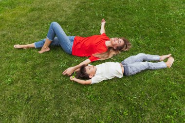 Mutlu bir anne ve küçük sevimli bir oğul yazın açık havada, halka açık bir parkta geziniyor. Aile zamanı, birliktelik, ebeveynlik ve mutlu çocukluk kavramı..