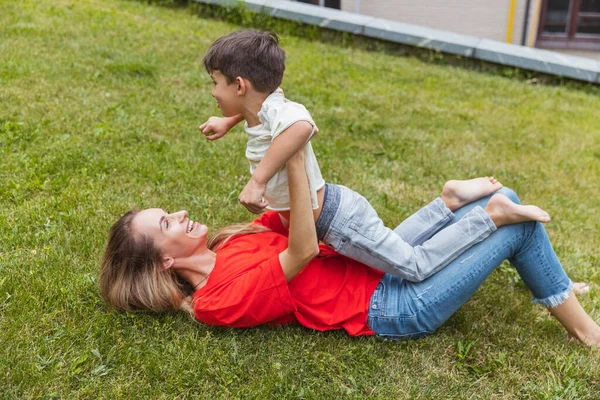 Mãe feliz e pequeno filho bonito passeando na rua, parque público na hora de verão, ao ar livre. Tempo de família, união, parentalidade e conceito de infância feliz. — Fotografia de Stock