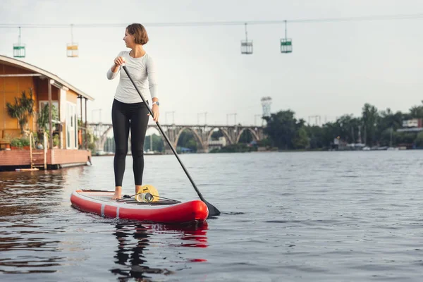 Fiatal kaukázusi nő, sportoló, turista áll a táblán, SUP, egyedül gyakorol. Aktív élet, sport, szabadidős tevékenység koncepciója — Stock Fotó