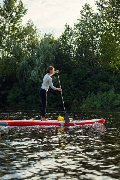 Fiatal kaukázusi nő, sportoló, turista áll a táblán, SUP, egyedül gyakorol. Aktív élet, sport, szabadidős tevékenység koncepciója — Stock Fotó