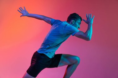 Kafkas profesyonel erkek atlet portresi, atlet eğitimi pembe stüdyo arka planında mavi neon filtreyle izole edilmiş, ışık. Kaslı, sportif bir adam. Arka plan