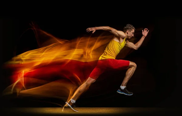 Retrato de joven, atleta profesional, corredor en movimiento y acción aislado sobre fondo oscuro. Efecto estroboscopio. — Foto de Stock