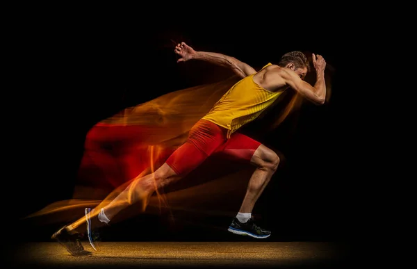 Портрет молодого человека, профессионального спортсмена, бегуна в движении и действие изолированы на темном фоне. Эффект стробоскопа. — стоковое фото