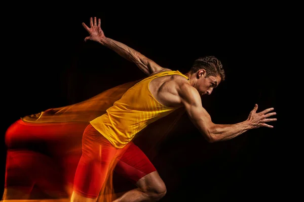 Retrato de joven, atleta profesional, corredor en movimiento y acción aislado sobre fondo oscuro. Efecto estroboscopio. — Foto de Stock