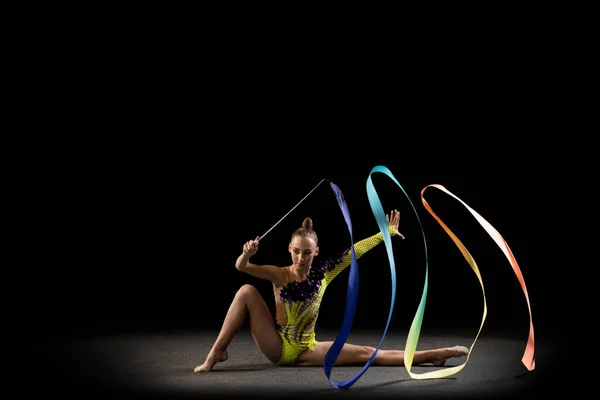 Une sportive émotionnelle, artiste de gymnastique rythmique isolée sur fond sombre en rayon de lumière. Concept de sport, action, aspiration, beauté, mode de vie actif — Photo