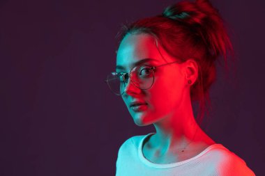 Koyu mor arka planda, neon ışıklı, filtreli tatlı, romantik bir kızın portresi. İnsan duyguları kavramı, yüz ifadesi.