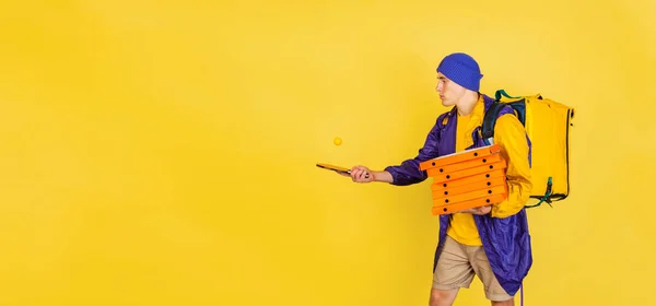 Retrato cómico de un joven, repartidor de uniforme aislado sobre fondo amarillo del estudio. Concepto de humor, seguridad, servicio. Colores complementarios —  Fotos de Stock