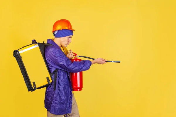 Retrato em quadrinhos de jovem, entregador de uniforme isolado em fundo de estúdio amarelo. Conceito de humor, segurança, serviço. Cores complementares — Fotografia de Stock