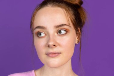 Mor, eflatun renkli stüdyo arka planındaki tatlı, güzel kızın yüzünü kapat. İnsan duyguları kavramı, yüz ifadesi, doğal güzellik, gençlik