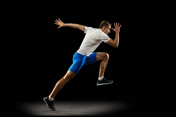 Retrato de hombre musculoso, deportivo, atleta masculino, entrenamiento de corredor aislado en el fondo oscuro del estudio con foco. Concepto de acción, movimiento, juventud, estilo de vida saludable. —  Fotos de Stock
