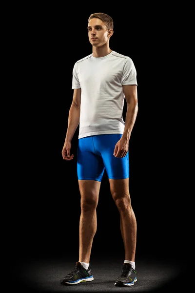 Portret van blanke professionele mannelijke atleet in sportuniform geïsoleerd op donkere studio-achtergrond. Een gespierde, sportieve man. Concept van actie, beweging, jeugd, gezonde levensstijl. — Stockfoto