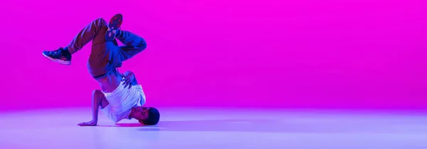 Flyer met dansende man, breakdanser in actie, beweging in moderne kleding geïsoleerd over heldere magenta achtergrond in danszaal in neon licht. — Stockfoto