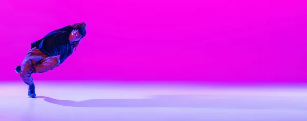 Флайер с танцующим мужчиной, брейк-дансер в действии, движение в современной одежде на ярком пурпурном фоне в танцевальном зале в неоновом свете. — стоковое фото