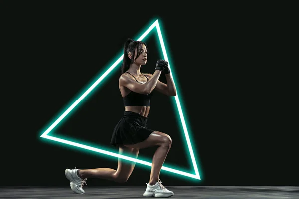 Genç bayan sporcular antrenman yapıyor, siyah arka planda ışık üçgeni ile izole edilmiş. Soyut ayrımcılık, aktif yaşam tarzı konsepti, güzellik, sporda hareket — Stok fotoğraf