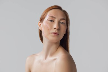 Yüzünde oklar olan genç, güzel ve sağlıklı bir kadının yakın plan portresi. Spa, ameliyat, yüz gerdirme ve cilt bakımı konsepti