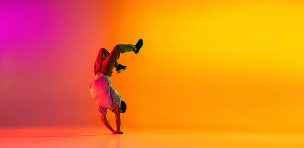 Genç ve şık bir adamla broşür, dansçı eğitimi günlük kıyafetler içinde dans pistinde izole edilmiş pembe arka plan üzerinde neon ışıklı dans.. — Stok fotoğraf