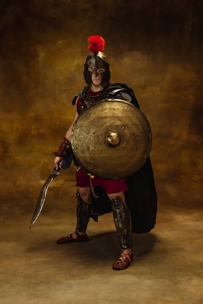 Retrato de persona medieval, hombre brutal, guerrero o caballero en equipo de guerra aislado sobre fondo oscuro vintage. Comparación de épocas, arte, historia, concepto de estilo retro —  Fotos de Stock