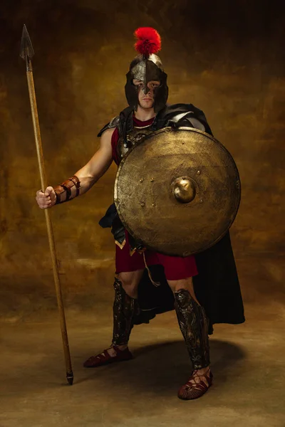 Retrato completo de persona medieval, hombre brutal, guerrero o caballero en equipo de guerra aislado sobre fondo oscuro vintage. Comparación de épocas, arte, historia, concepto de estilo retro —  Fotos de Stock