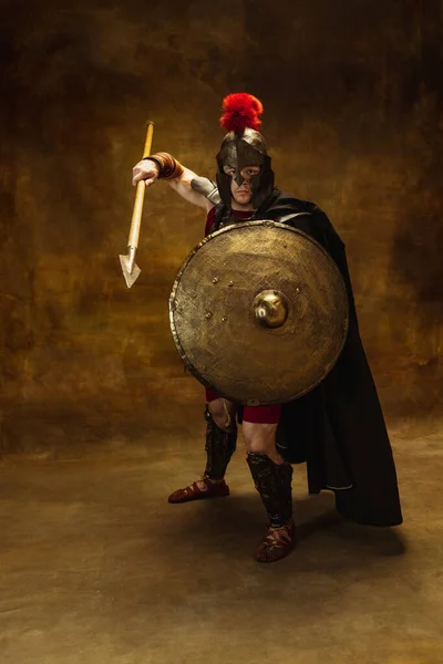 Retrato de persona medieval, hombre brutal, guerrero o caballero en equipo de guerra aislado sobre fondo oscuro vintage. Comparación de épocas, arte, historia, concepto de estilo retro —  Fotos de Stock