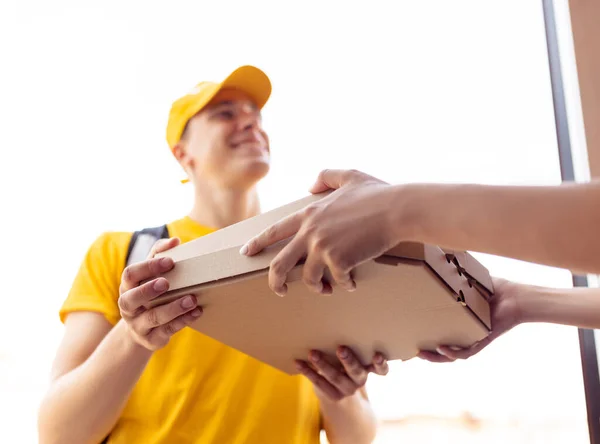 Jonge bezorger in geel uniform levert order aan klanten, klanten, kopers. Werk, carrière, verschillende beroepen concept. Idee van gemak, snelheid, comfort, veiligheid, service. — Stockfoto