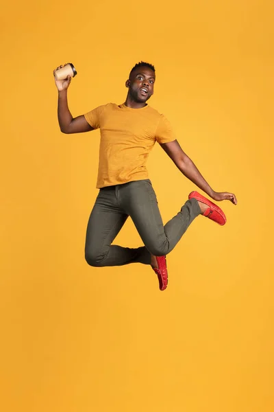 Portrait de jeune homme africain en tenue décontractée isolé sur fond studio de couleur jaune. Concept d'émotions humaines, expression faciale, jeunesse, sentiments, publicité. — Photo