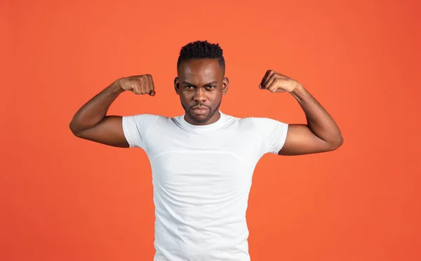 Retrato de un joven africano con ropa casual aislado sobre fondo de estudio de color rojo. Concepto de emociones humanas, expresión facial, juventud, sentimientos, ad. —  Fotos de Stock