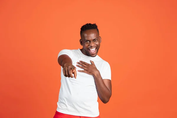 Heureux jeune homme africain en vêtements décontractés isolé sur fond de studio de couleur rouge. Concept d'émotions humaines, expression faciale, jeunesse, sentiments, publicité. — Photo