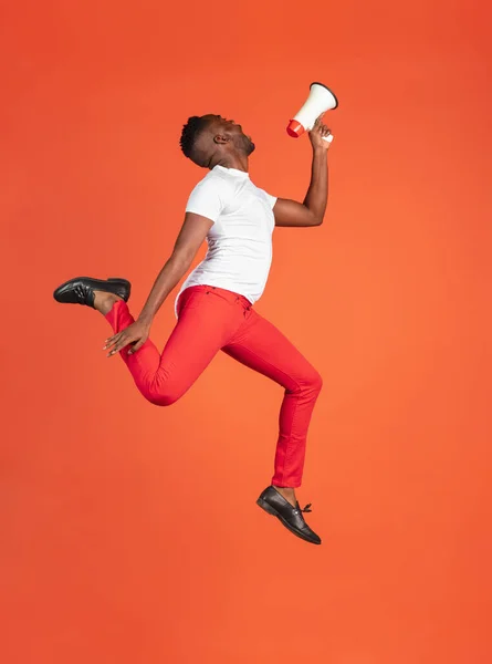 Portrait de jeune homme africain en tenue décontractée isolé sur fond studio couleur rouge. Concept d'émotions humaines, expression faciale, jeunesse, sentiments, publicité. — Photo