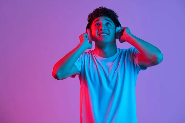 Stilvolle junge asiatische Mann isoliert über lila Farbe Studio Hintergrund in rosa Neonlicht. Konzept menschlicher Emotionen, Mode, Schönheit, Jugend — Stockfoto