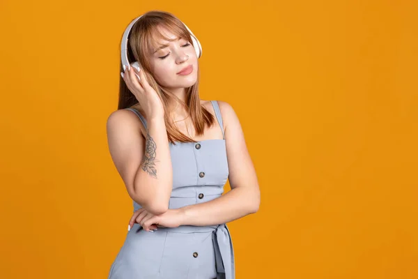 Retrato de menina bonita ouvindo música isolada no fundo do estúdio amarelo. Conceito de emoções humanas, expressão facial, juventude, vendas, anúncio. — Fotografia de Stock