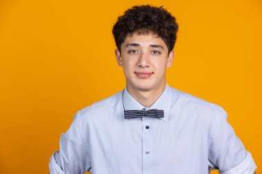 Genç kıvırcık adamın yarım boy portresi sarı stüdyo arka planında izole edilmiş ve reklam için kopyalanmış. İnsan duyguları, moda, güzellik, gençlik kavramı