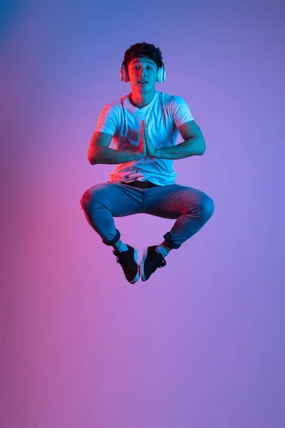 Elegante jovem asiático homem isolado sobre cor lilás estúdio fundo em luz de néon rosa. Conceito de emoções humanas, moda, beleza, juventude — Fotografia de Stock