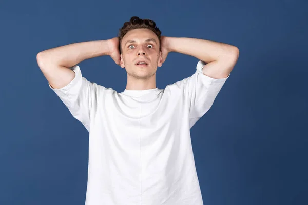 Um jovem caucasiano isolado no fundo do estúdio cor azul marinho. Conceito de emoção humana, expressões faciais, juventude, sentimentos, ad. — Fotografia de Stock