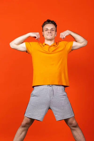 Портрет молодого кавказького чоловіка, який стоїть ізольований на оранжевому тлі кольорової студії. Концепція людських емоцій, виразів обличчя, молоді, почуттів, реклами. — стокове фото