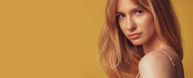 Kahverengi stüdyo arka planında, makyajsız, bronzlaşmış güzel bir kadının yakın plan portresi. Doğal güzellik konsepti. El ilanı