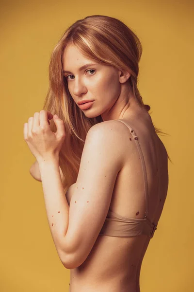 Una joven hermosa mujer bronceada en lencería posando aislada sobre fondo de estudio marrón. Concepto de belleza natural. — Foto de Stock