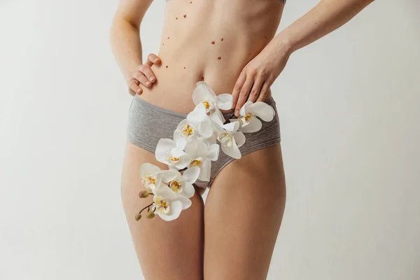 Όμορφο σώμα της νεαρής καυκάσιας γυναίκας με λευκό λουλούδι απομονωμένο σε γκρι φόντο στούντιο. Έννοια φυσικής ομορφιάς — Φωτογραφία Αρχείου