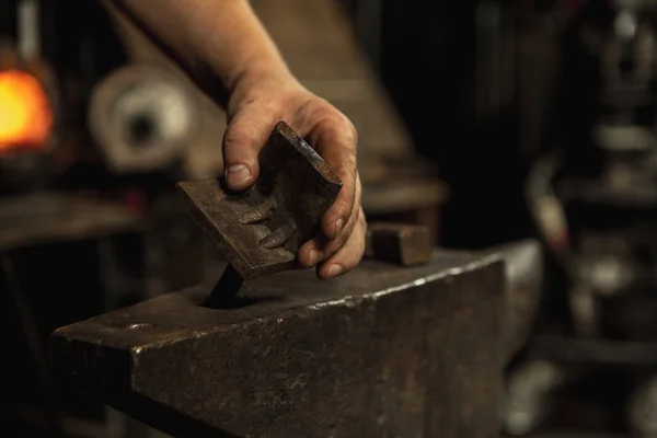 Primer plano trabajando poderosas manos de herrero macho forjar un producto de hierro en un herrero. Martillo, metal caliente rojo y yunque. Concepto de trabajo, profesiones retro — Foto de Stock