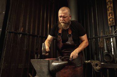 Sakallı adam, demirci demircideki erimiş metali havai fişeklerle elle dövüyor. Çalışma anlayışı, geçmişe dönük meslekler, aile meslekleri