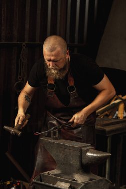 Sakallı adam, demirci demircideki erimiş metali havai fişeklerle elle dövüyor. Çalışma anlayışı, geçmişe dönük meslekler, aile meslekleri