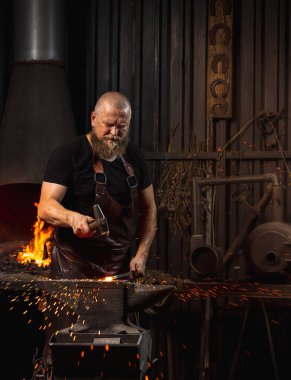 Sakallı adam, demirci demircideki erimiş metali havai fişeklerle elle dövüyor. Çalışma anlayışı, geçmişe dönük meslekler, aile meslekleri