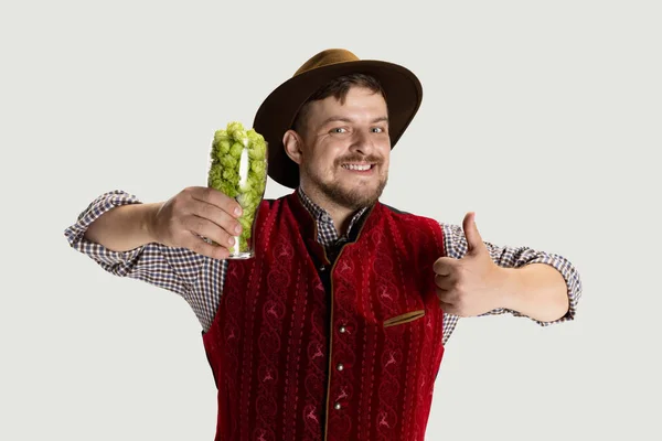 Feliz homem sorridente vestido com traje tradicional bávaro segurando copos de cerveja cheios de quente selvagem e cevada. Celebração, oktoberfest, conceito de festival. — Fotografia de Stock