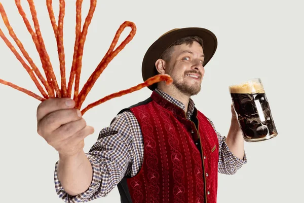 Primer plano del hombre barbudo, camarero en traje tradicional austriaco o bávaro sosteniendo taza, vaso de cerveza negra oscura aislado sobre fondo gris — Foto de Stock