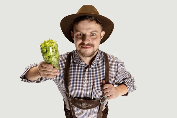 Feliz homem sorridente vestido com traje tradicional bávaro segurando copos de cerveja cheios de quente selvagem e cevada. Celebração, oktoberfest, conceito de festival. — Fotografia de Stock