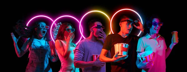 Colagem feita de jovens multiétnicos assistindo filme juntos isolado em fundo escuro em luz de néon multicolorido com forma luminescente geométrica circo — Fotografia de Stock